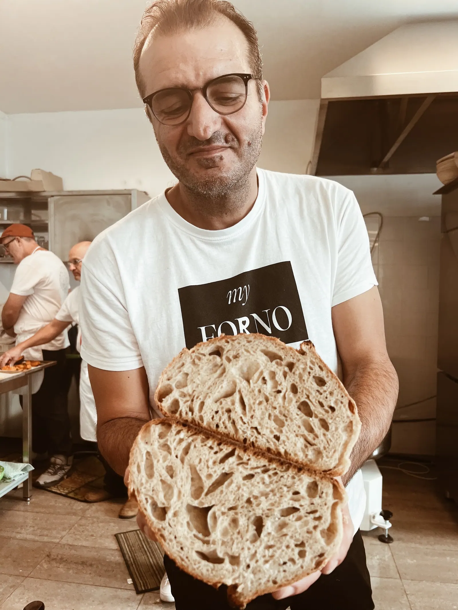 A baker holding a loaf split open to show the crumb