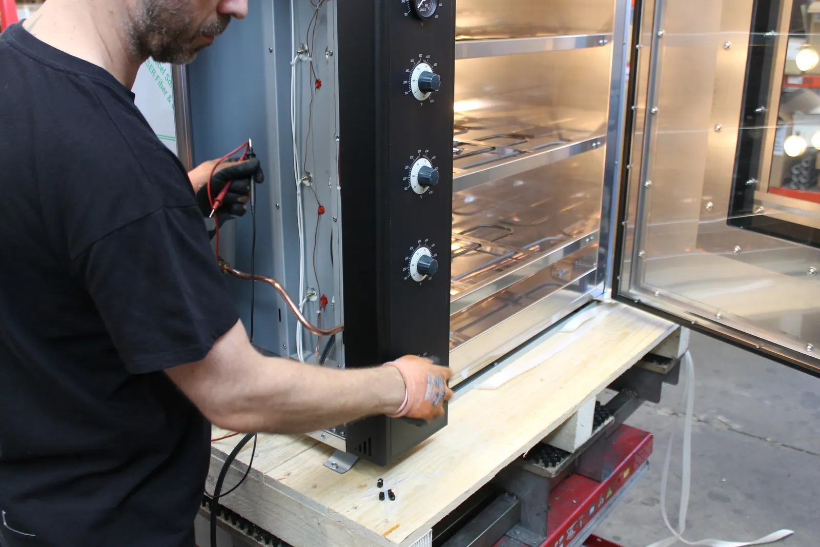 A worker wiring a MyForno oven by hand